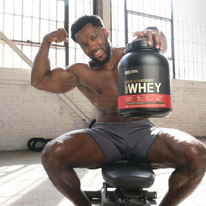 Athlete using Gold Standard Whey protein shake for post-training muscle recovery.